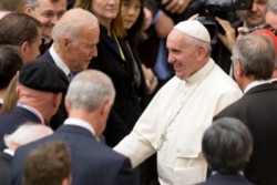 FILE - Pope Francis shakes hands with then U.S. Vice President Joe Biden as they take part in a conference being held at the Vatican, April 29, 2016.