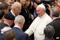 FILE - Pope Francis shakes hands with then U.S. Vice President Joe Biden as they take part in a conference being held at the Vatican, April 29, 2016.