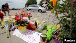 A man kneels at a make-shift memorial at the site of the police shooting of Philando Castile in Falcon Heights, Minnesota, July 7, 2016.