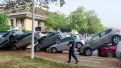 Warga berjalan di dekat mobil-mobil yang menumpuk akibat banjir di Picanya, dekat Valencia, Spanyol timur, pada 30 Oktober 2024. (Foto: AFP)