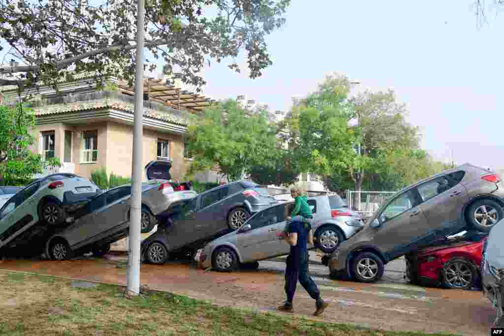 Warga berjalan melewati tumpukan mobil setelah banjir bandang di kawasan De La Torre, Valencia, sebelah selatan Valencia, Spanyol timur, yang telah menewaskan sedikitnya 70 orang. (AFP)&nbsp;