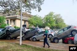 Residents walk near cars that floodwaters left piled up in eastern Spain, Oct. 30, 2024.