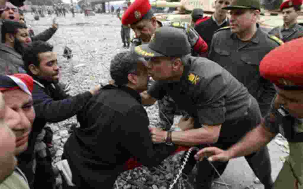 An anti-government protester is kissed by Gen. Hassan El-Rueini just outside Tahrir Square, Cairo, Egypt, Saturday, Feb. 5, 2011. State TV says the top leadership body of Egypt's ruling party, including the president's son Gamal Mubarak and the party secr