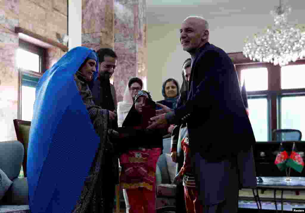 Sharbat Gula (L), the green-eyed &quot;Afghan Girl&quot; whose 1985 photo in National Geographic became a symbol of her country&#39;s wars, receives a key to an apartment from Afghanistan&#39;s President Ashraf Ghani, after she arrived in Kabul. Pakistan officials said Gula was deported to her native country.