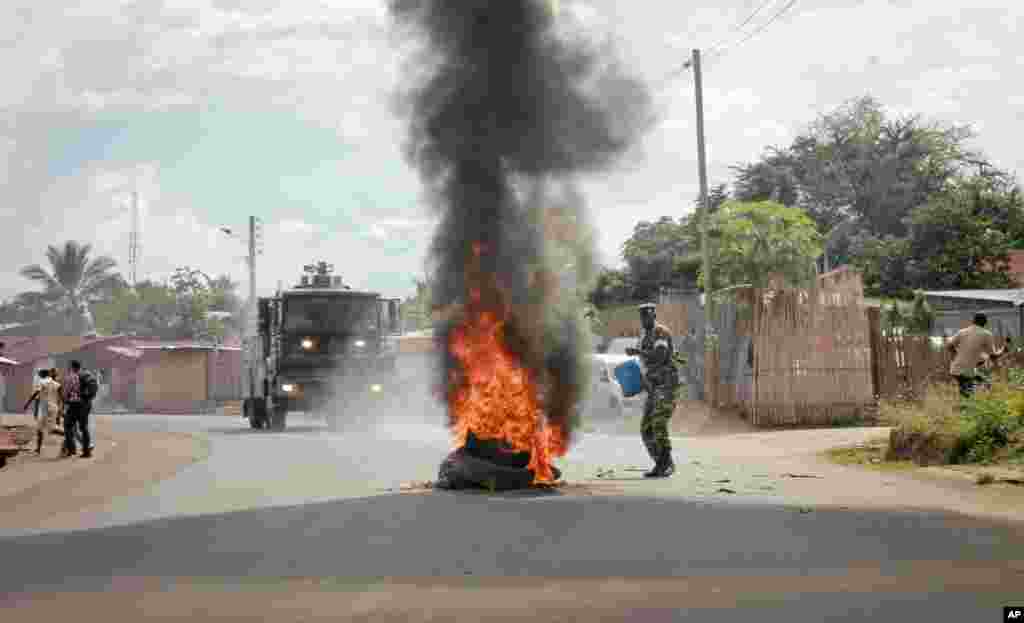Un soldat de l&#39;armée burundaise, avec un seau d&#39;eau, tente d&#39;éteindre le feu d&#39;un pneu brulé par les manifestants&nbsp; dans la capitale Bujumbura, Burundi, lundi 27 avril 2015.
