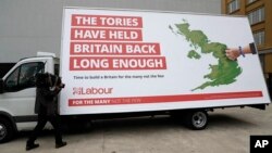 FILE - A cameraman films a poster being unveiled by Britain's opposition Labor party for the upcoming general election, in London, May 11, 2017.