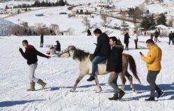 Seorang pria memegang kuda di atas salju di Resor Ski Elmadag, Ankara, setelah hujan salju turun di kawasan tersebut, 22 Januari 2021. (Adem ALTAN / AFP)