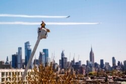 A utility worker watches the U.S. Navy's Blue Angels and the U.S. Air Force's Thunderbirds conduct "a collaborative salute" to honor those battling the COVID-19 pandemic with a flyover of New York and New Jersey, April 28, 2020.