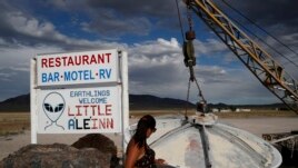 In this July 22, 2019 photo, Grace Capati looks at a UFO display outside of the Little A'Le'Inn, in Rachel, Nevada, the closest town to Area 51.