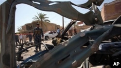 Iraqi security forces inspect the site of a suicide car bomber plowed his vehicle into a checkpoint outside a police building just outside the holy city of Najaf, Iraq, Monday, Aug. 15, 2011.