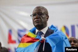 FILE —DRC gynaecologist and activist Denis Mukwege stands wrapped with national flag after he announced his candidacy for the December 2023 presidential election at Fatima Parish church in Kinshasa, October 2, 2023.