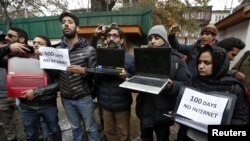 FILE - Kashmiri journalists display laptops and placards during a protest demanding restoration of internet service, in Srinagar, November 12, 2019. 