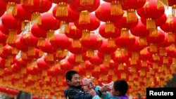 Children play with bubble toy guns under Chinese lunar New Year decorations at a park in Beijing, Jan. 24, 2014. 