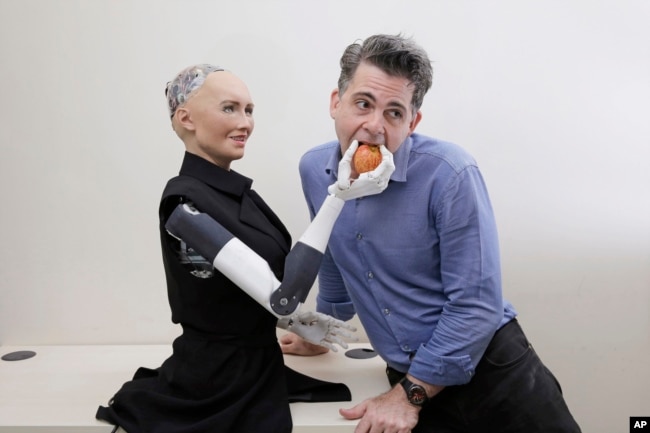FILE - David Hanson, the founder of Hanson Robotics, poses with his company's flagship robot, Sophia, a lifelike robot powered by artificial intelligence, in Hong Kong, Sept. 28, 2017.