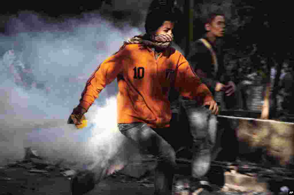 Seorang demonstran lari saat bentrokan dengan pasukan pengamanan di Alun-Alun Tahrir, Kairo (25/11).