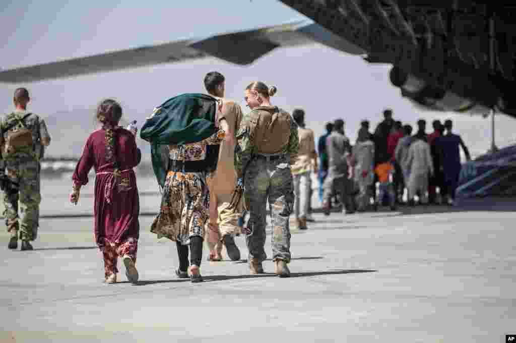 24일 카불 국제공항에서 아프가니스탄을 탈출하는 사람들이 미 해병대원의 안내를 받으며 미 공군 수송기에 오르고 있다.