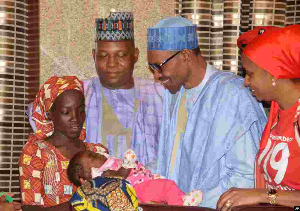 Nigeria President Muhammadu Buhari, second right, receives Amina Ali, the rescued Chibok school girl, at the Presidential palace in Abuja. The first Chibok teenager to escape from Boko Haram's Sambisa Forest stronghold was flown to the capital and met with the president, even though her freedom puts pressure on the government to do more to rescue 218 other missing girls.
