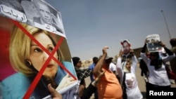 A supporter of Egypt's former President Hosni Mubarak holds a defaced picture of U.S. ambassador to Egypt Anne Patterson (bottom) and U.S. President Barack Obama (top) as others shout slogans against members of the Muslim Brotherhood and supporters of ousted Egyptian President Mohamed Morsi, before Mubarak's trial in Cairo, July 6, 2013.