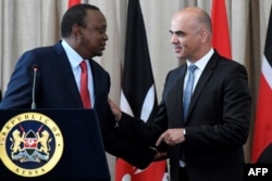 FILE - Swiss President Alain Berset, right, speaks with his Kenyan counterpart President Uhuru Kenyatta during a joint press conference at the State House in Nairobi, July 9, 2018.