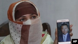 In this May 22, 2019 photo, Sumaira a Pakistani woman, shows a picture of her Chinese husband in Gujranwala, Pakistan. (AP Photo/K.M. Chaudary) 