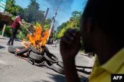 A man sets fire to the bodies of alleged gang members in Petion-Ville, a suburb of Port-au-Prince, Haiti, Nov. 19, 2024.