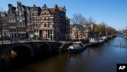 A boy in a wetsuit takes advantage of the ban on recreational boats and jumps into one of the normally crowded canals on a warm spring day in the city center of Amsterdam, Netherlands, April 5, 2020. 