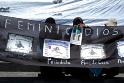 FILE - Women hold a banner reading "femicide" and with pictures of their relatives during a rally to condemn violence against women in La Paz, Bolivia, Nov. 25, 2014.