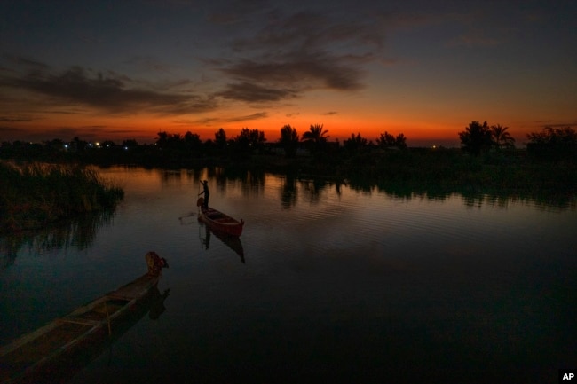 The sun sets as an Iraqi fishermen heads out on his boat in the Chibayish marshes of southern Iraq, in Dhi Qar, Iraq, Saturday, Nov. 19, 2022.