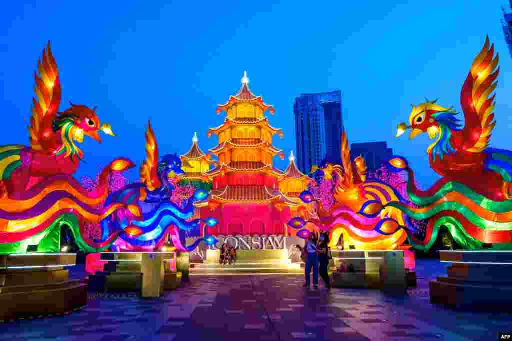 People visit a festive installation of illuminated pagodas and mythical animals erected outside a shopping mall to celebrate the upcoming Lunar New Year in Bangkok, Thailand.