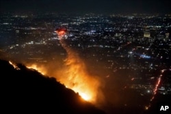 Вертоліт скидає воду на палаючі Голлівудські пагорби Лос-Анджелеса, середа, 8 січня 2025 р. Фото: AP/Ethan Swope