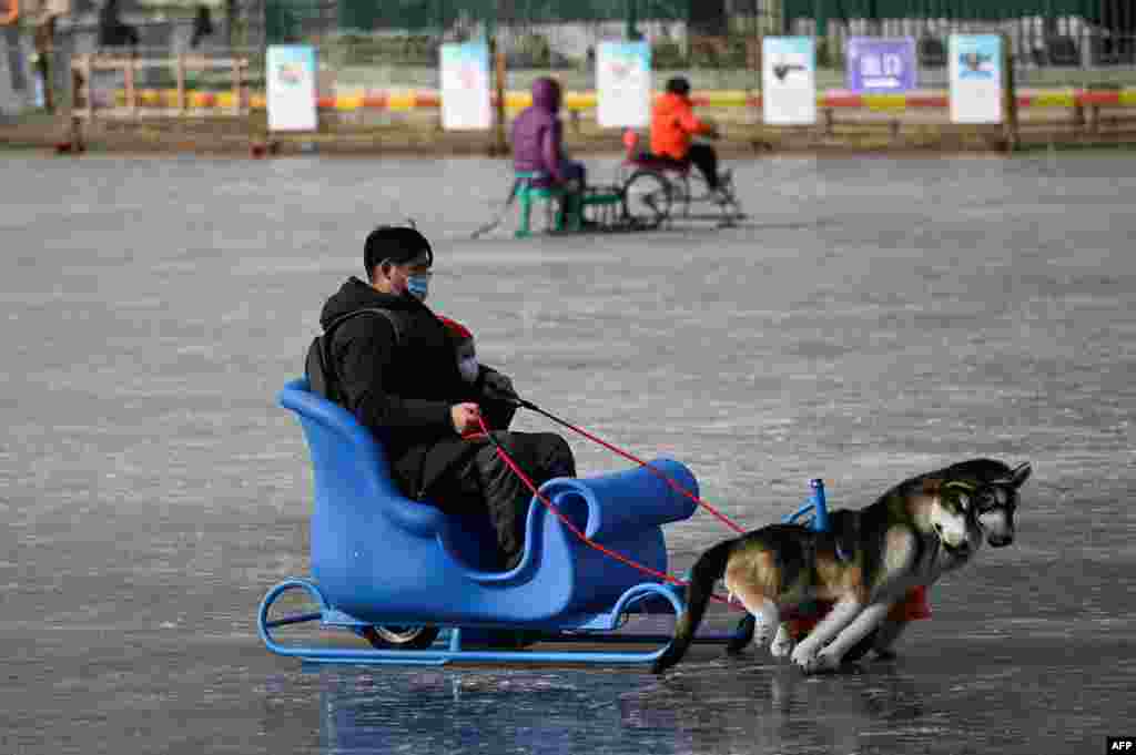 A man and a child use a sled on a frozen lake in Beijing.