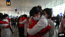 Medical staff from Jilin Province (in red) hug nurses from Wuhan after working together during the COVID-19 coronavirus outbreak during a ceremony before leaving as Tianhe Airport is reopened in Wuhan in China's central Hubei province on April 8, 2020.