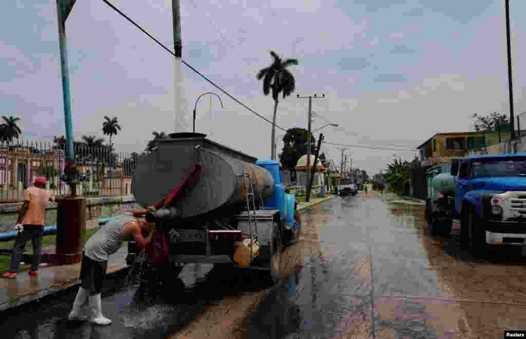 ARCHIVO - Un conductor se refresca mientras llena el tanque de un camión cisterna en La Habana, Cuba, el 3 de julio de 2023.&nbsp;