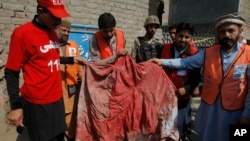Pakistani volunteers show a blood-soaked burqa of a woman who was killed in an a suicide bombing in the town of Shabqadar, Charsadda district, Pakistan, March 7, 2016.