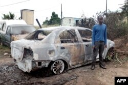 A foreign national from Zimbabwe stands by one of his two cars set alight after he survived a petrol bomb attack at his home in Illovo, some 55 kilometers south of Durban, South Africa, April 19, 2015