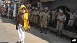 A Hindu holyman walks past Indian securitymen standing guard in Ayodhya, India, 28 Sep 2010