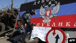 A pro-Russian armed man displays a banner at a check point outside the eastern Ukrainian city of Slavyansk, Apr. 26, 2014.