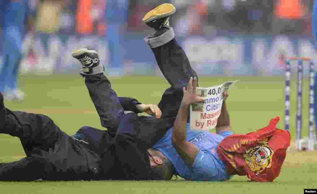 A protester is tackled to the ground after running onto the field holding a sign protesting against Sri Lanka&#39;s President Mahinda Rajapaksa during the ICC Champions Trophy semi-final match between Sri Lanka and India at Cardiff Wales Stadium in Wales, Britain.