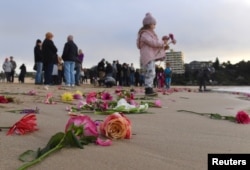 Relatives and friends of Justine Damond, who was shot by a Minneapolis police officer over the weekend, stand near flowers after they held a vigil at Sydney's Freshwater Beach in Australia, July 19, 2017.