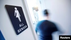 FILE - A bathroom sign welcomes both genders at the Cacao Cinnamon coffee shop in Durham, N.C., May 3, 2016. 