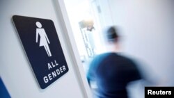 FILE - A bathroom sign welcomes both genders at the Cacao Cinnamon coffee shop in Durham, N.C., May 3, 2016. 