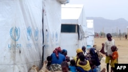 FILE - FILE - Nigerian refugees sit by a UNHCR tent in the refugee camp of Minawao, on the border of Nigeria at the extreme north of Cameroon.