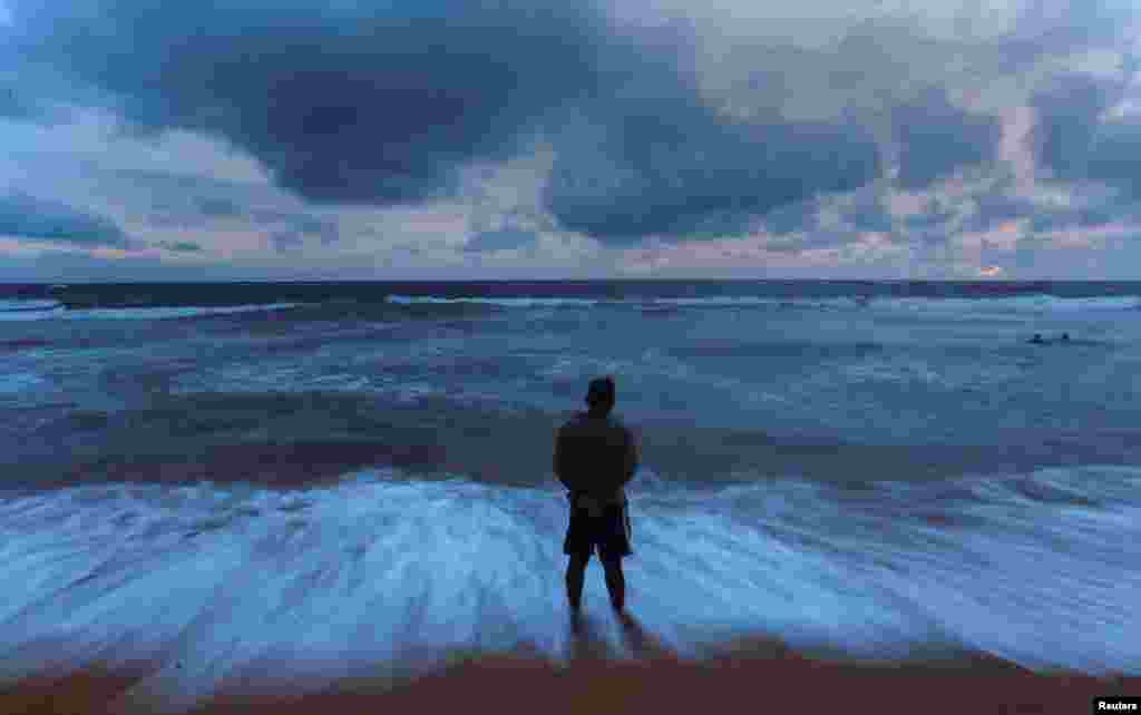 A man stands on a beach before the rain during the monsoon season in Colombo, Sri Lanka. 