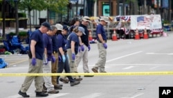 Members of the FBI's evidence response team walk the scene one day after a mass shooting in downtown Highland Park, Ill. Tuesday, July 5, 2022. (AP Photo/Charles Rex Arbogast)