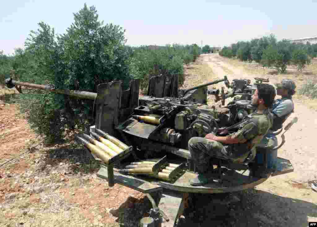 A handout picture released by the Shaam News Network shows rebel fighters manning an anti-aricraft gun near Hama, Syria, June 4, 2013.