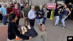 Let Vargas ofrece rollos de canela a los votantes en un puesto de votación en Austin, Texas, donde las primarias demócratas del martes 6 de marzo.