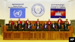 In this photo released by the Extraordinary Chambers in the Courts of Cambodia, Judges and clerks of the U.N.-backed war crimes tribunal are standing inside the court hall of the U.N.-backed war crimes tribunal in Phnom Penh, Cambodia, Thursday, Aug. 7, 2