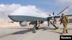 Seorang tentara Angkatan Udara AS melintas di depan MQ-9 Reaper drone, yang tiba untuk membantu serangan terhadap Taliban, di Pangkalan Udara Kandahar, Afghanistan, 23 Juni 2018. 