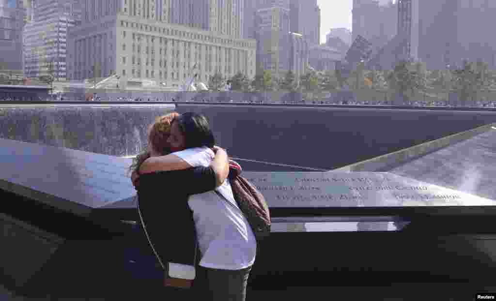Grissel Valentin (L) and Eileen Esquilin, who both lost family members in the 9/11 attacks, embrace at the edge of the North Pool of the 9/11 Memorial during a ceremony marking the 12th anniversary of the 9/11 attacks on the World Trade Center in New York.