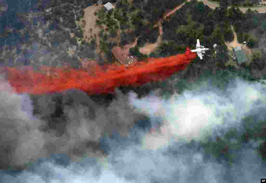 An aircraft lays down a line of fire retardant between a wildfire and homes in the dry, densely wooded Black Forest area northeast of Colorado Springs, Colorado, June 13, 2013.